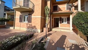 A residential building with a balcony, brick facade, and a well-maintained garden. - Villa Kadal a 100 Metri dal Mare (Grosseto)