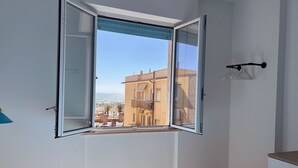 Una habitación con un ventanal grande, una cama y un aparador de madera.