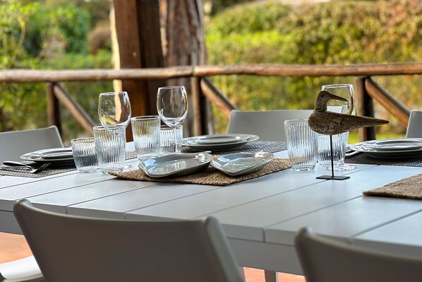 A dining table set with plates, glasses, and cutlery, with a bird figurine on the table. - Villa Molletta a Punta Ala con Piscina (Castiglione della Pescaia)