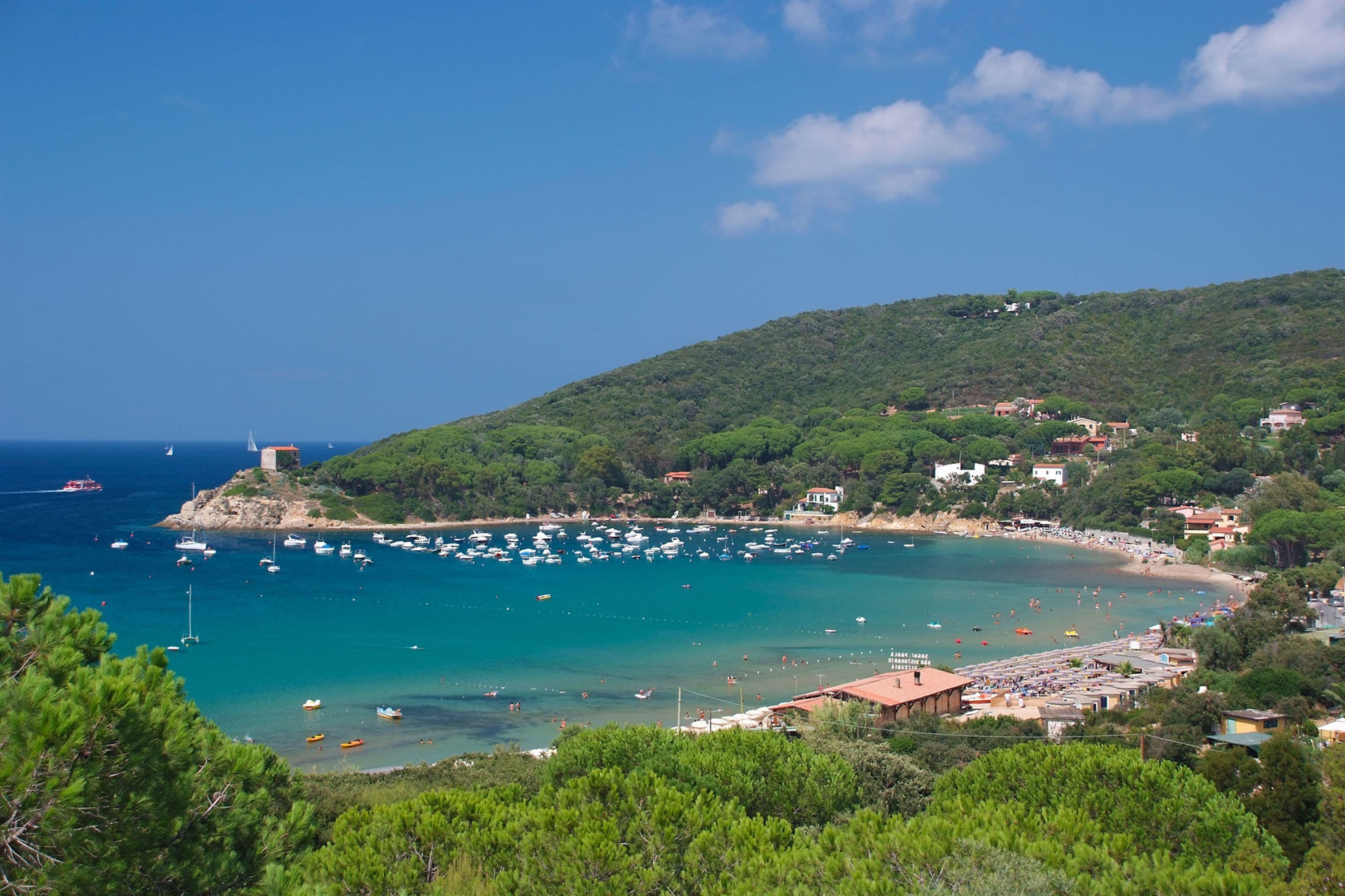 A coastal town with a beach, boats, and houses.