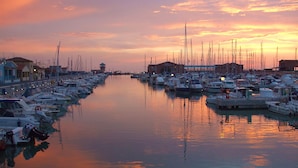 A marina with boats docked along the water's edge, buildings on the shore, and a clear sky. - Appartamento Giglio Vicino al Mare (Grosseto)
