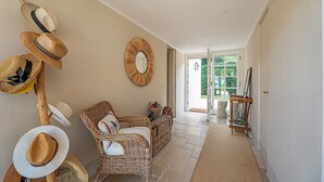 A hallway with wicker furniture, a mirror, and a collection of hats on a wall. - Villa Ondina - Isola d Elba (Marciana Marina)