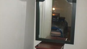 A mirror with a dark frame mounted on a wooden dresser against a plain wall. - Small affordable Studio near UQAM. (Montréal)