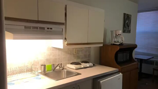 A compact kitchen with a sink, a coffee maker, and a microwave. - Small affordable Studio near UQAM. (Montréal)
