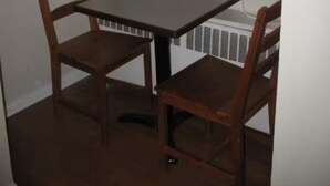 A corner room with a small table and two chairs, a window, and a radiator. - Small affordable Studio near UQAM. (Montréal)