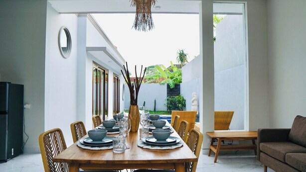 A dining area with a wooden table set for six, surrounded by wicker chairs. - Milmai Villa (Bali)