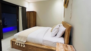 A bedroom with a wooden bed, white bedding, a wooden nightstand, and a wall-mounted decor piece. - Milmai Villa (Bali)