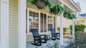 A porch with two rocking chairs and hanging planters.