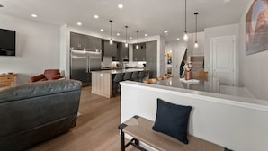 A modern kitchen with a central island, recessed lighting, and a dining area with bar stools. - Canyon Country Oasis: Desert Color Lagoon + Beaches (St. George)