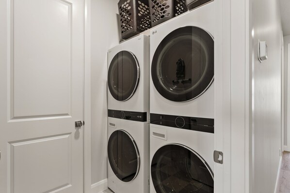A laundry room with four stacked front-loading washing machines.