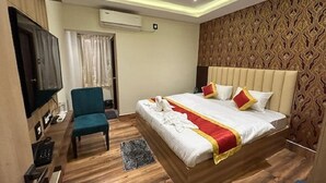 A hotel room with a bed, a desk, a chair, a television, and a patterned wall. - Hotel Royal Orbit  (Bhubaneshwar)
