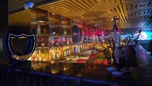 A bar area with shelves of bottles, a shield-shaped decoration, and a patterned ceiling. - Hotel Royal Orbit  (Bhubaneshwar)