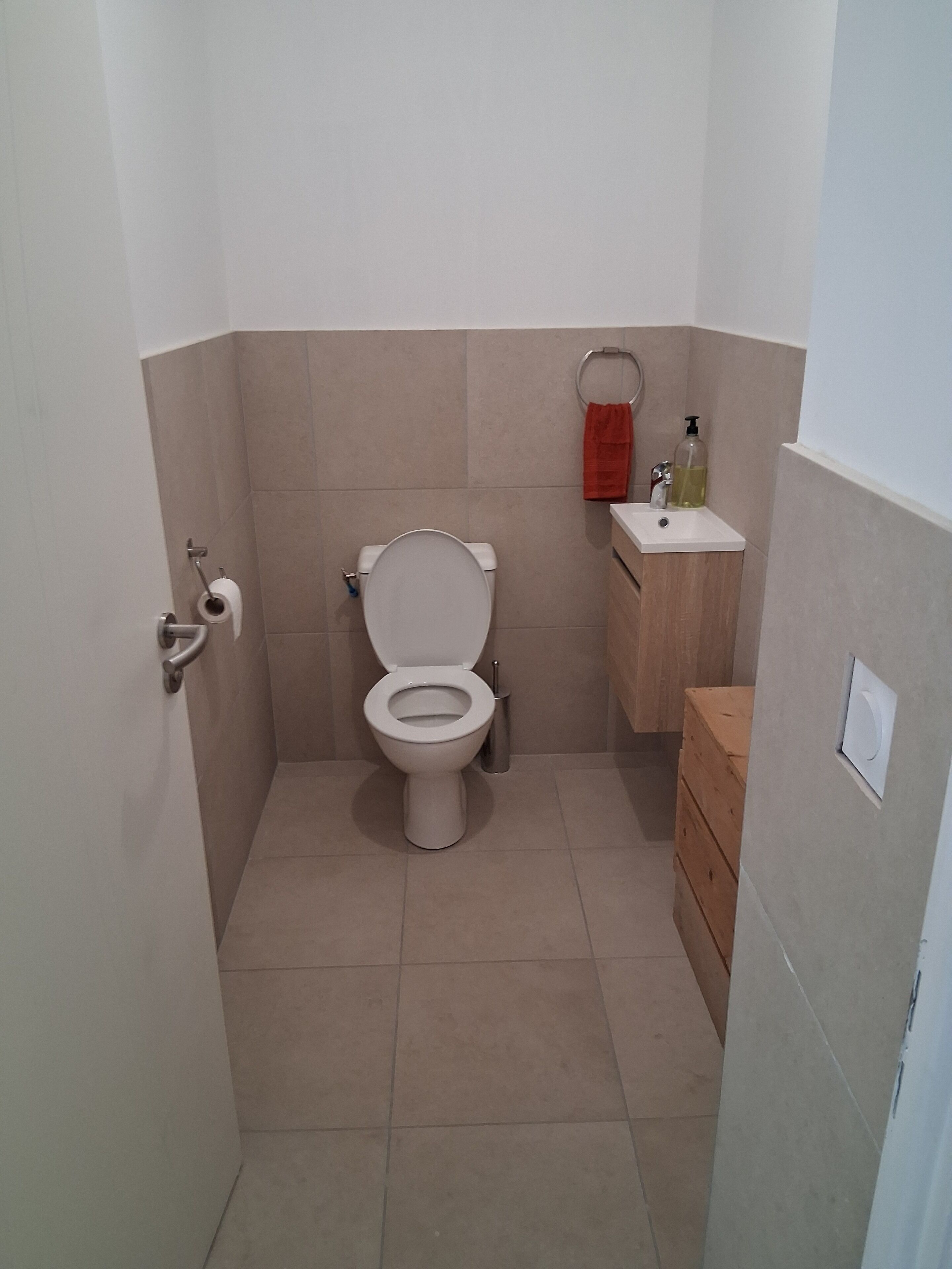 A small bathroom with a toilet, a sink, and a wooden cabinet.