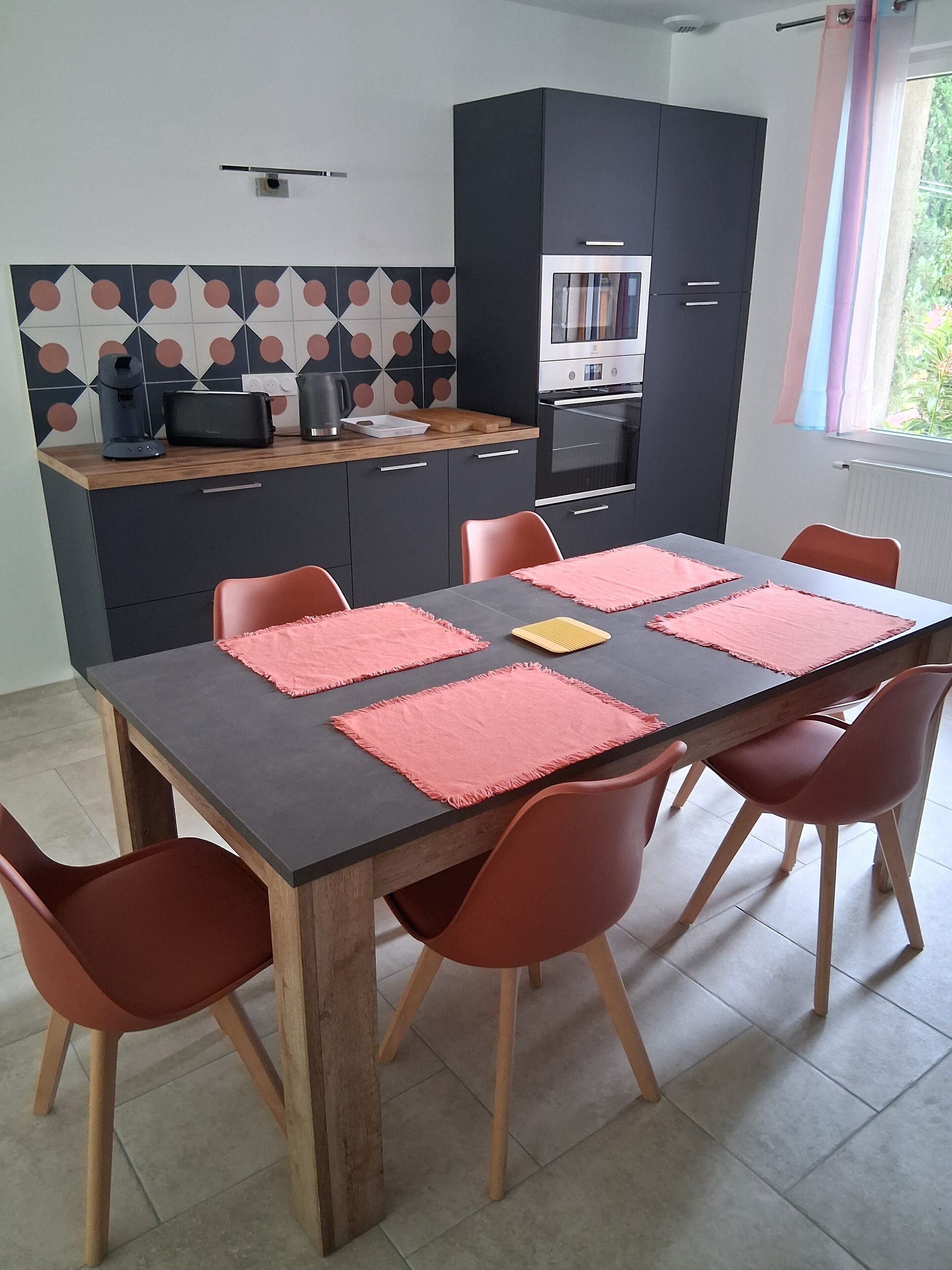 A modern kitchen with a dining table, chairs, and a coffee machine.