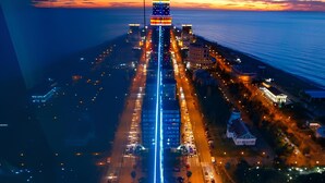 An aerial view of a cityscape at dusk with illuminated buildings and a busy road. - Orbi Panorama Sea Resort (Batumi)