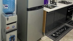 Une cuisine compacte équipée d’un réfrigérateur, d’un four à micro-ondes, d’un distributeur d’eau et d’une cuisinière à gaz.