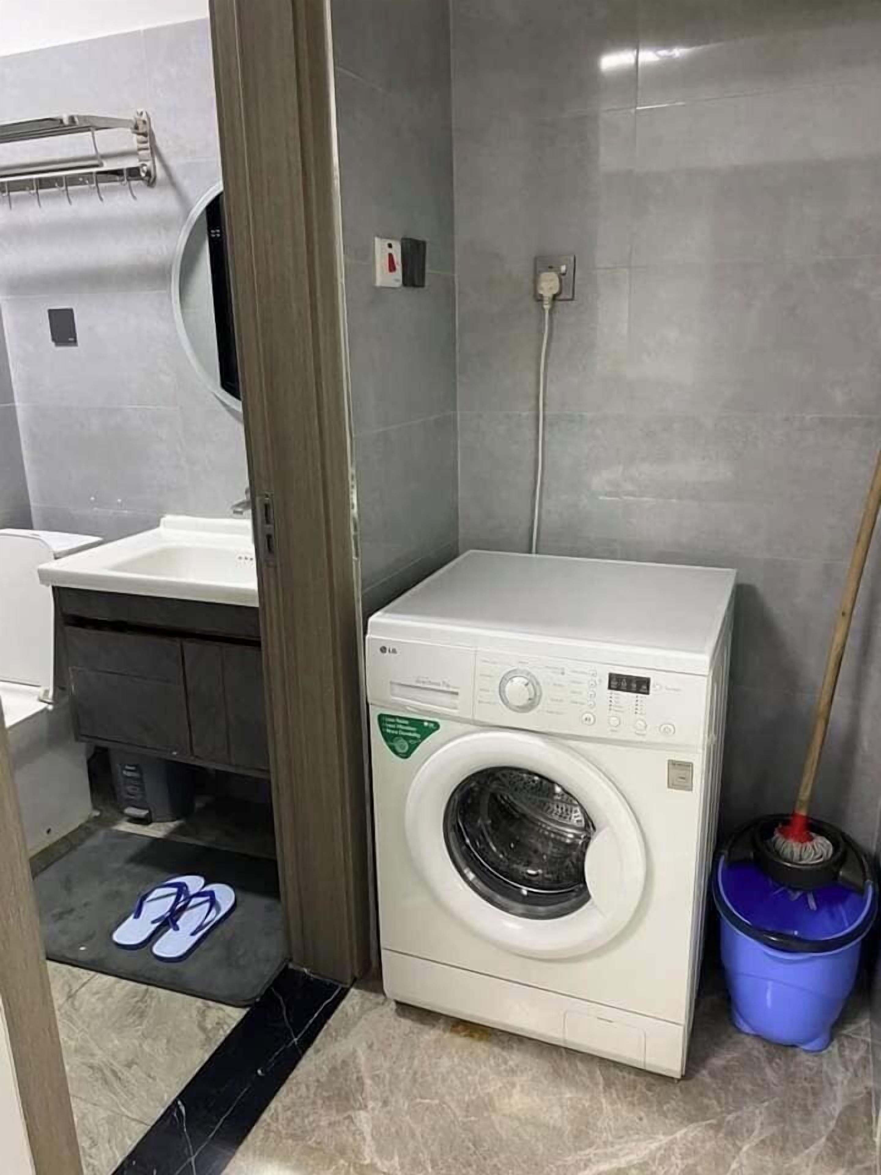 A compact laundry room with a washing machine, a sink, and a mop.