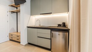 Una cocina moderna con horno empotrado, refrigerador de acero inoxidable y un televisor de pantalla plana sobre la encimera.