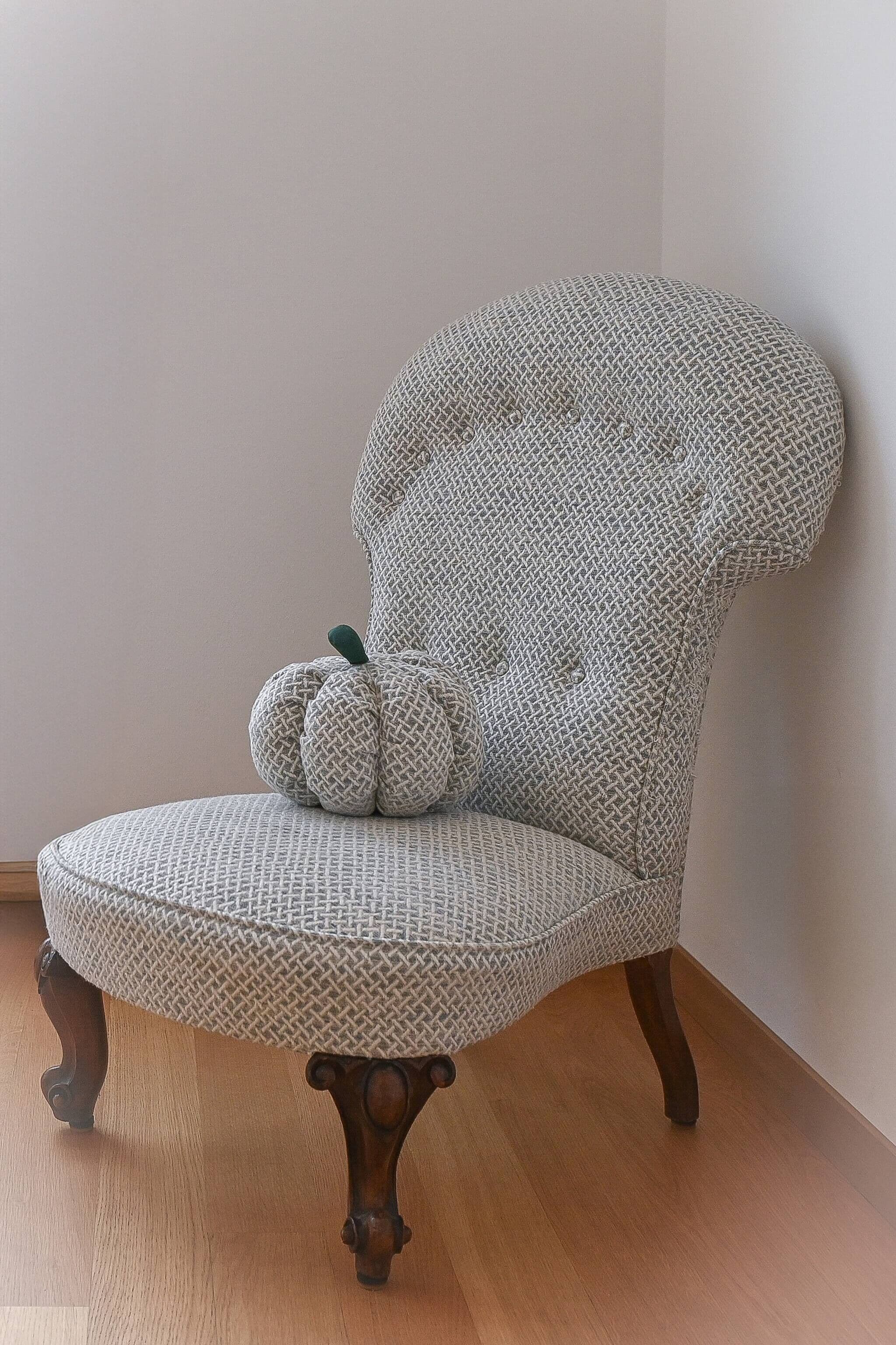 A chair with a woven fabric seat and backrest, paired with a matching cushion. The chair has a classic wooden base with carved details.