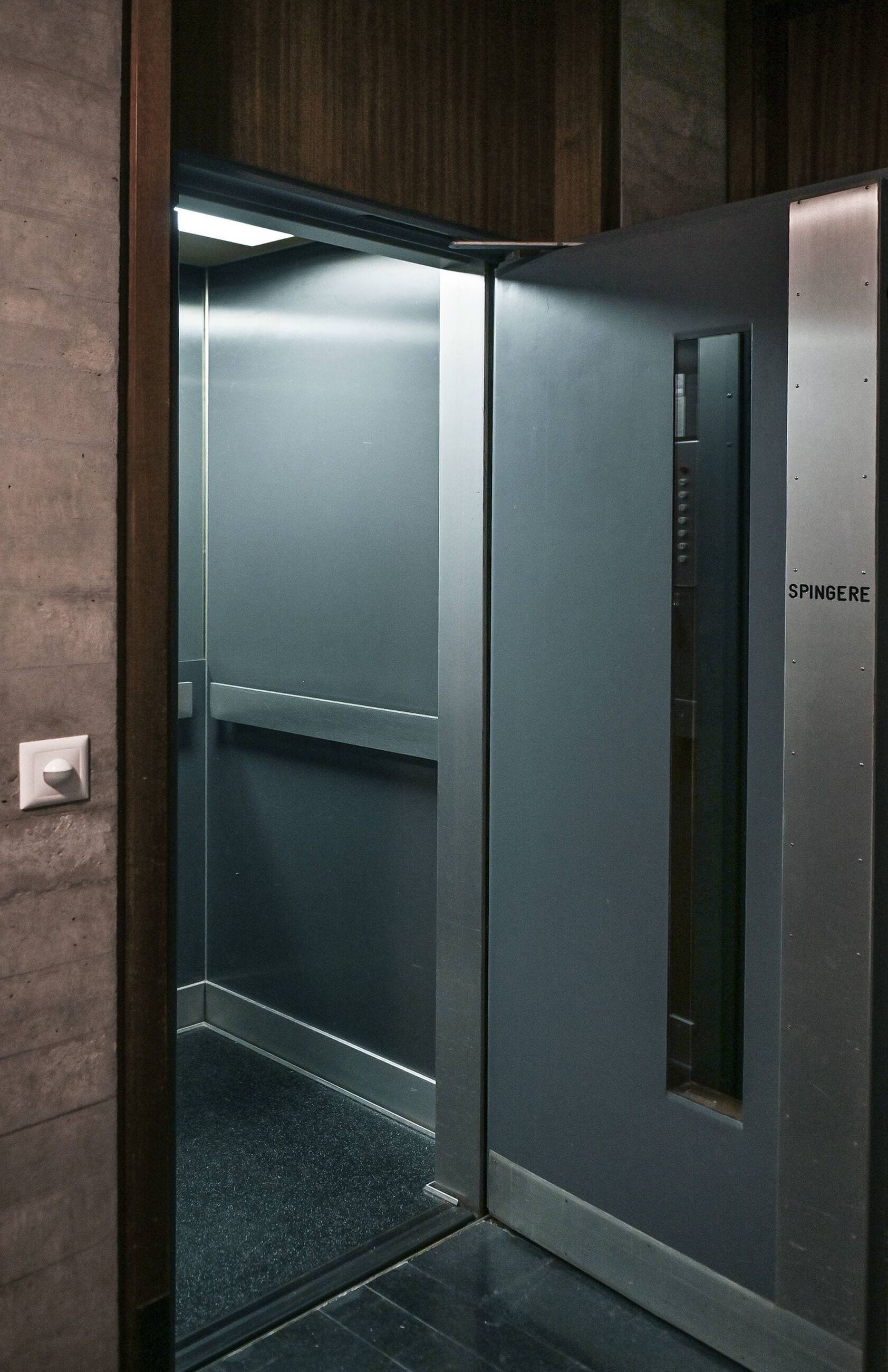 Ein moderner Aufzug mit metallischer Oberfläche und Bedienfeld auf der rechten Seite.