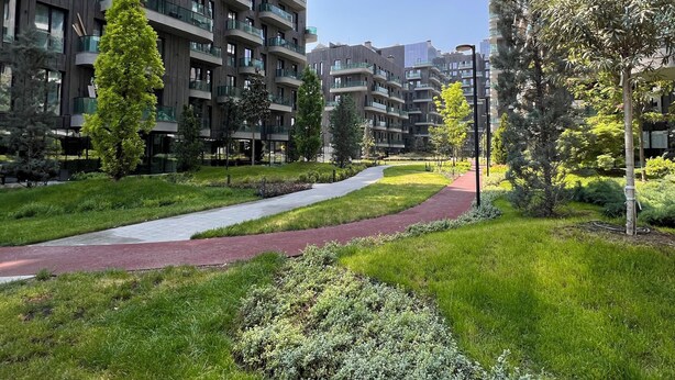 Un immeuble résidentiel moderne doté de nombreux balcons, d’un jardin bien entretenu et d’un chemin clairement défini.