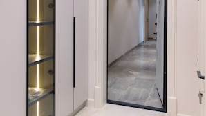 Un couloir avec une armoire à miroir, une porte donnant sur une autre pièce et un sol en marbre.