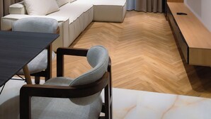 Un salon moderne avec un canapé d’angle, une table à manger et un téléviseur à écran plat fixé au mur.