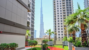 Ein modernes Wohngebäude mit Dachgarten, Palmen und Blick auf den Burj Khalifa.
