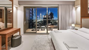 Ein modernes Hotelzimmer mit einem großen Bett, einem Schreibtisch und Blick auf eine nächtliche Skyline.