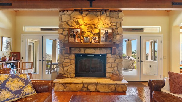 A stone fireplace with framed photos, a leather sofa, and a wooden coffee table in a cozy living room. - 40 Acres + Home Office + Views | Paso Robles | Skyeranch-30 Day Rental (San Miguel)
