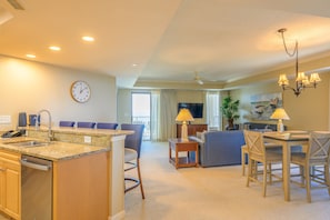A hotel room with a kitchen area, dining table, and seating. - Ocean Front, 1602 Royale Palms 3 Bedroom Condo (Myrtle Beach)
