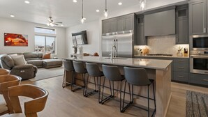 A modern kitchen with grey cabinets, stainless steel appliances, and a central island with bar stools.