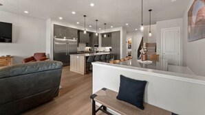 A modern kitchen with a central island, recessed lighting, and a dining area with bar stools.