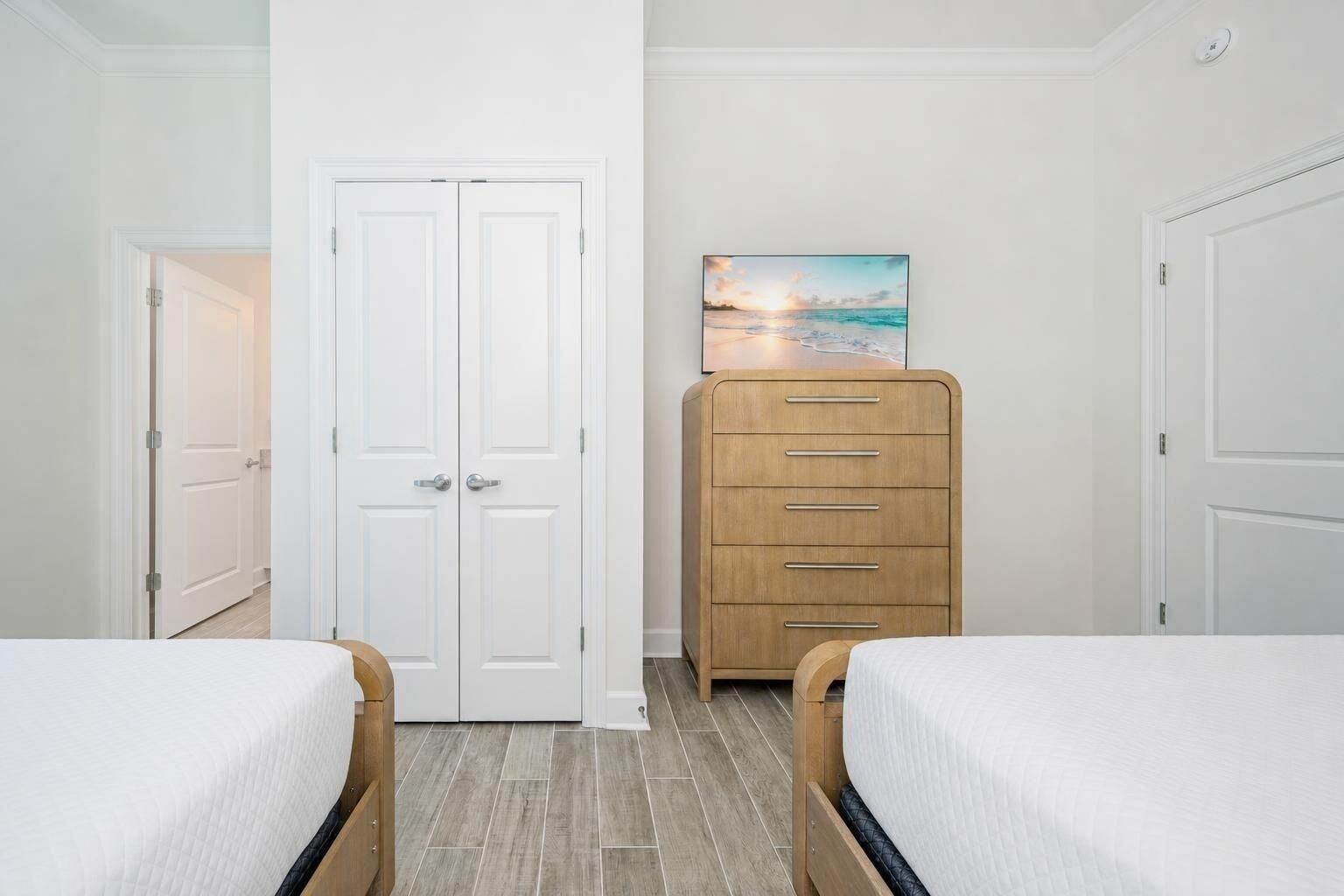 A bedroom with two beds, a wooden dresser, and a painting on the wall.
