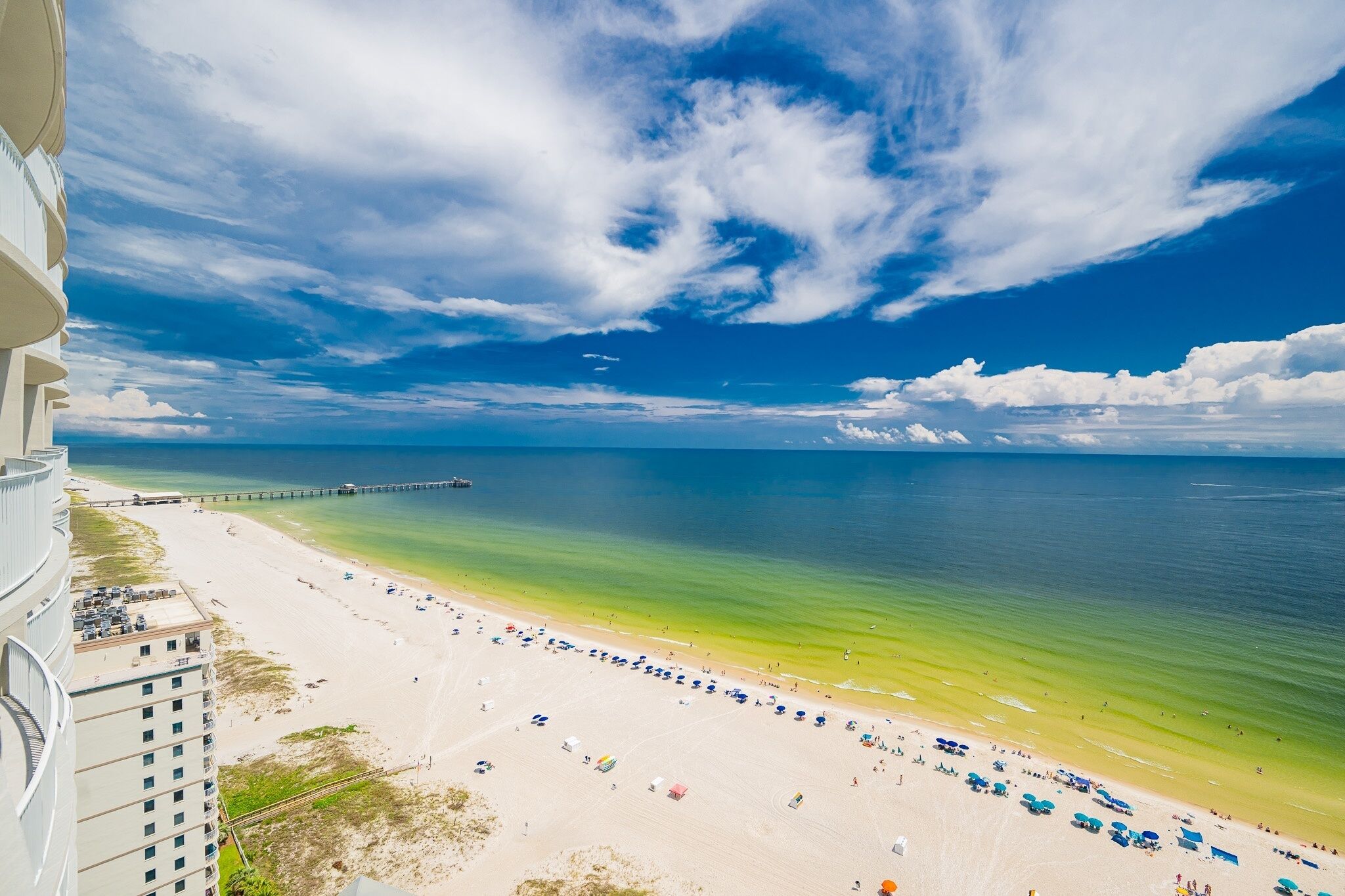 Une plage avec une jetée, un ciel dégagé et une vue sur l  ’océan.
