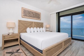 Ein Hotelzimmer mit einem großen Bett, einem Holzkopfteil, zwei Nachttischen mit Lampen, einem großen Fenster mit Blick und einem gemusterten Teppich.