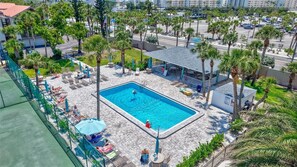 A rooftop pool area with lounge chairs and umbrellas, surrounded by palm trees and a view of the city. - Siesta Beach Retreat 2 Bedroom Townhouse (Siesta Key)