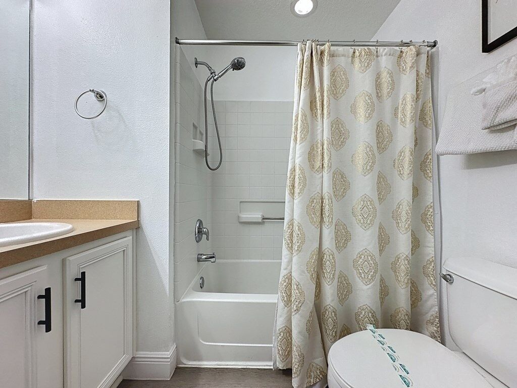 A bathroom with a shower, toilet, and sink.