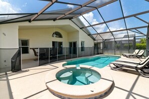 A covered outdoor swimming pool with a hot tub, lounge chairs, and a glass enclosure. - Gated 4 Bed With Pool And Spa Close To Disney 4 Bedroom Villa (Davenport)