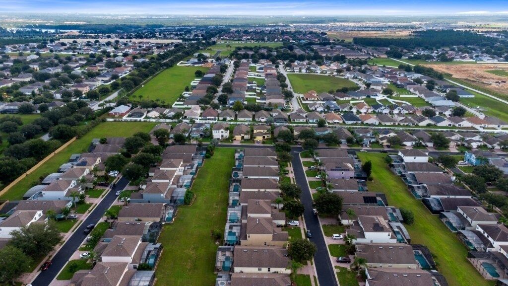 An aerial view of a residential area with houses, streets, and green spaces.