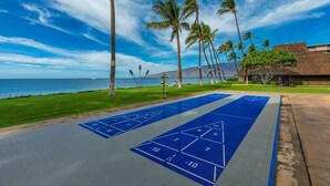 A shuffleboard court with a clear view of the ocean and palm trees in the background. - Maalaea Surf B1 2 Bedroom Condo (Kihei)