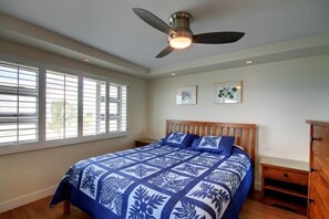 A bedroom with a bed, a ceiling fan, and a window with blinds.
