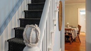 A staircase with a patterned carpet and a white wall with a rope decoration.