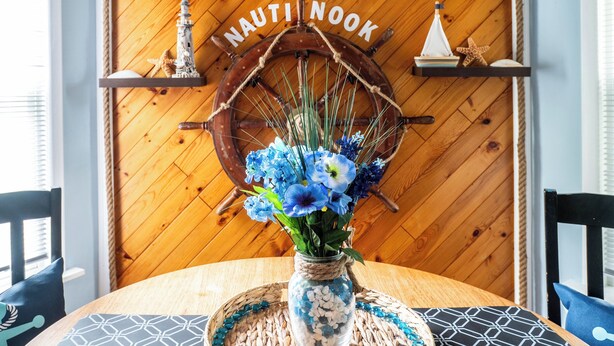 A wooden wall with nautical decor, including a ship wheel and a sign reading "THE NAUTINOOK".