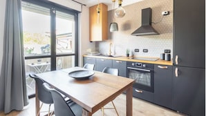 A modern kitchen with a wooden table, black cabinets, and a large window.