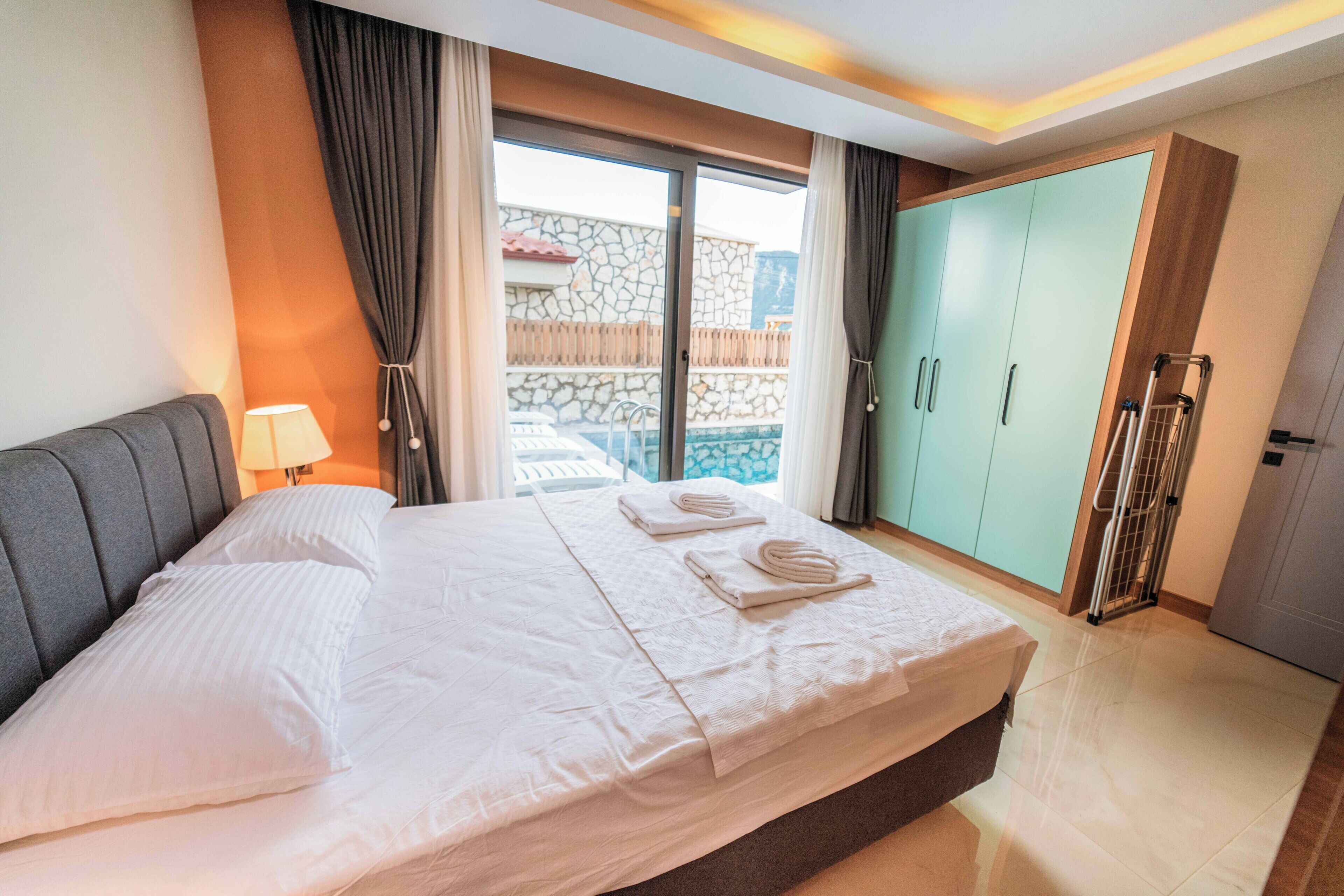 A hotel room with a large bed, a balcony with a stone wall, and a wardrobe.