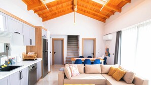 A modern kitchen with a central island, a dining area with a table and chairs, and a living room with a sofa and a coffee table. - Villa Meyra (Kas)