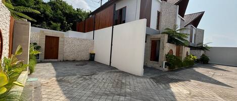 A modern house with a stone facade, a wooden door, and a tiled patio area.