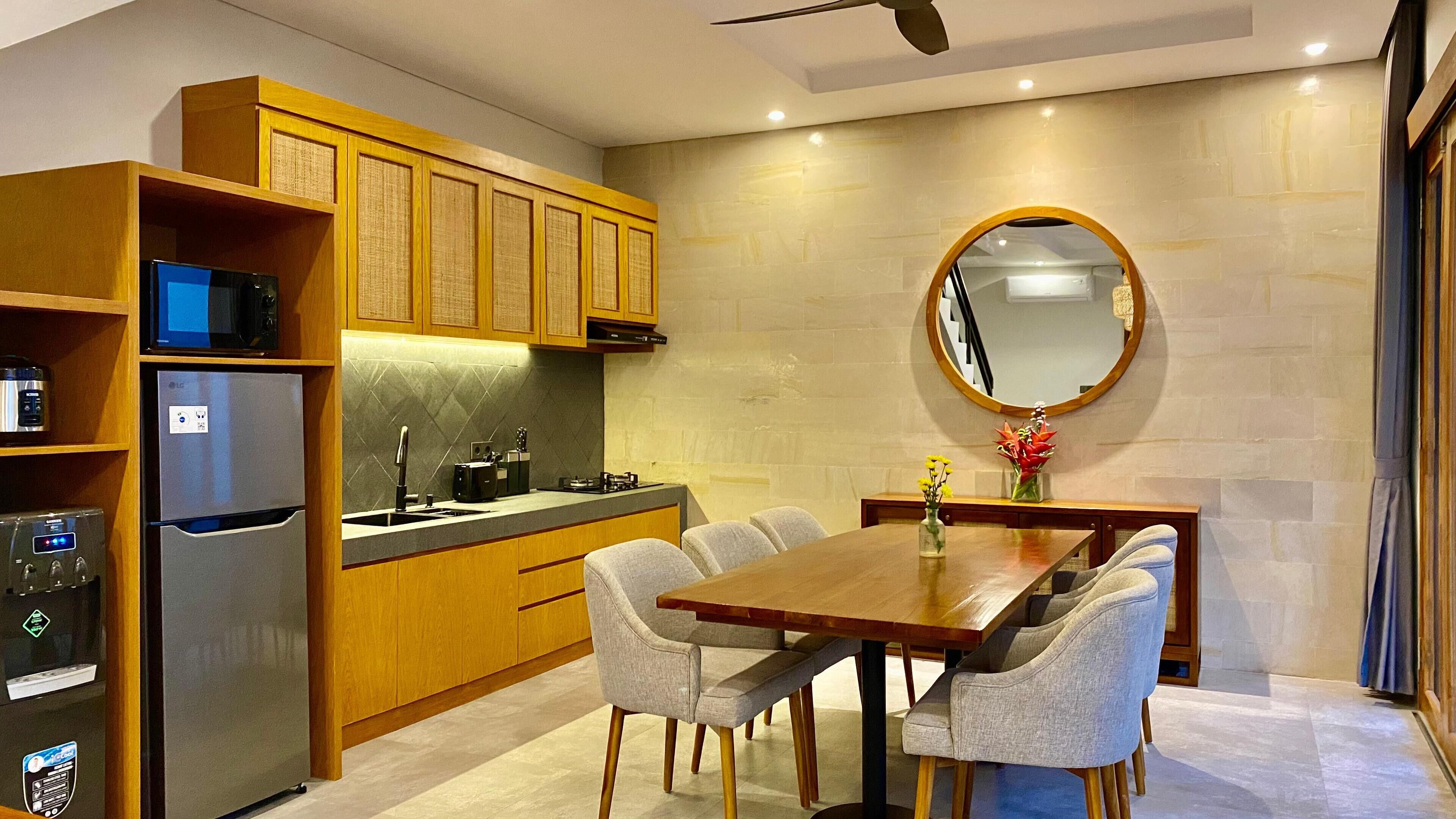 A modern kitchen with wooden cabinets, a built-in microwave, and a stainless steel refrigerator.