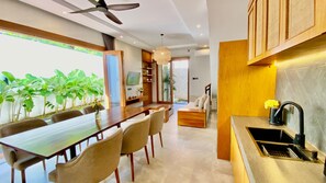 Une cuisine moderne avec un coin repas, comprenant une longue table en bois, des chaises et un four encastré.
